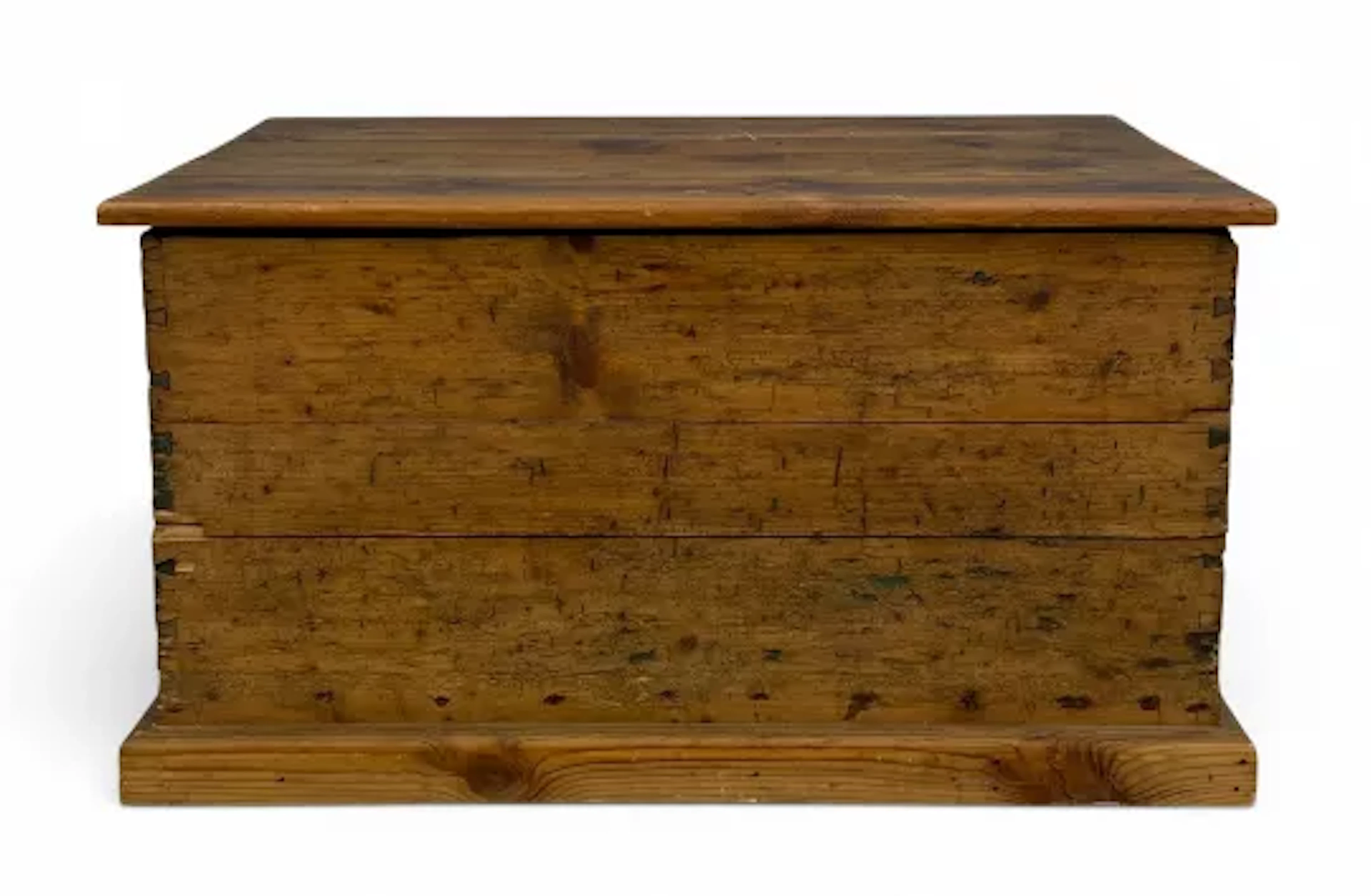 A vintage pine blanket chest with a plank top and iron handles on