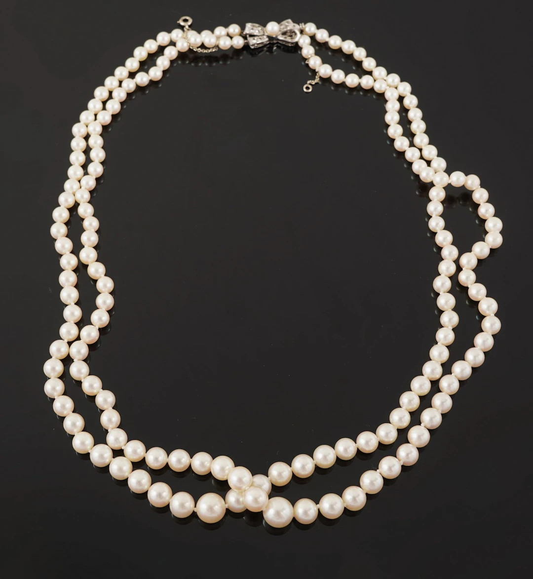 A necklace featuring two rows of cascading cultured pearls, - Lot 102