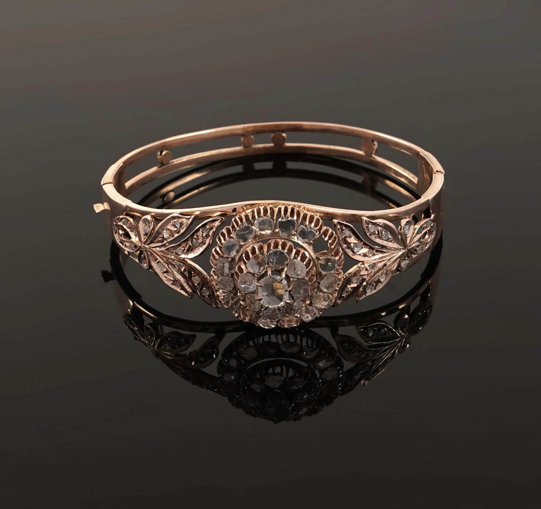 A 14k gold (585) clasp-style bangle featuring a circular rel - Lot 155