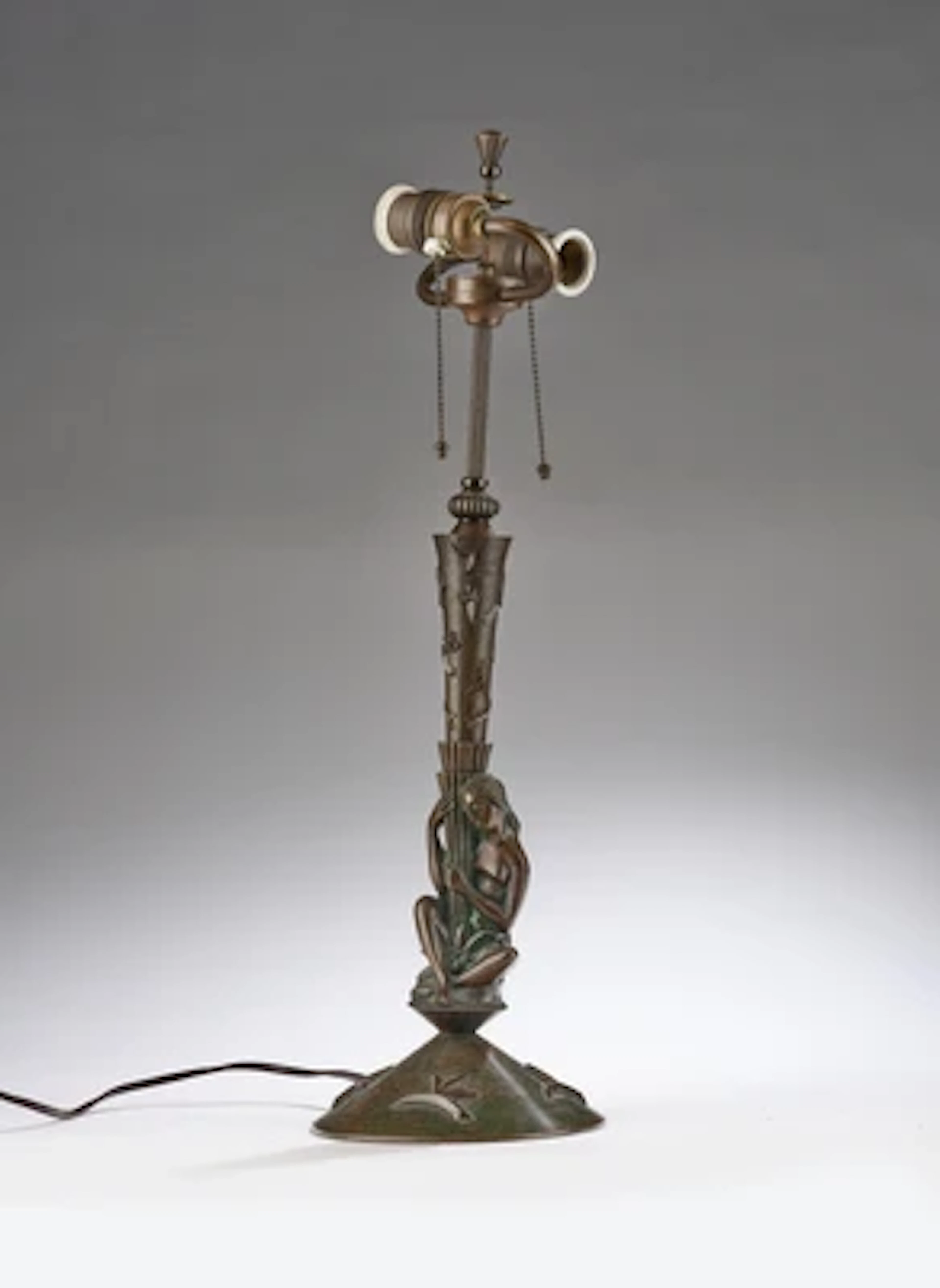 A brass lamp base with seated female figure and decorations in the