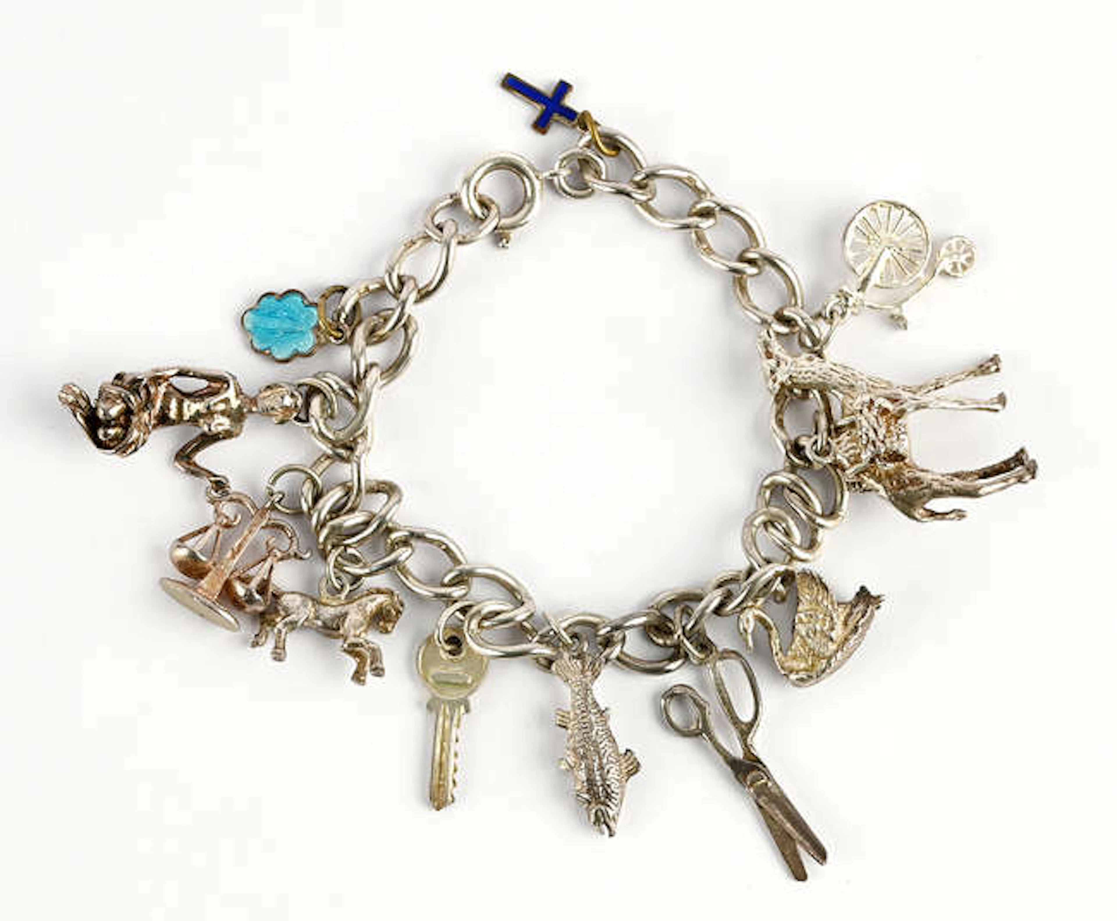 A silver charm bracelet with eleven charms, including a pair of scissors