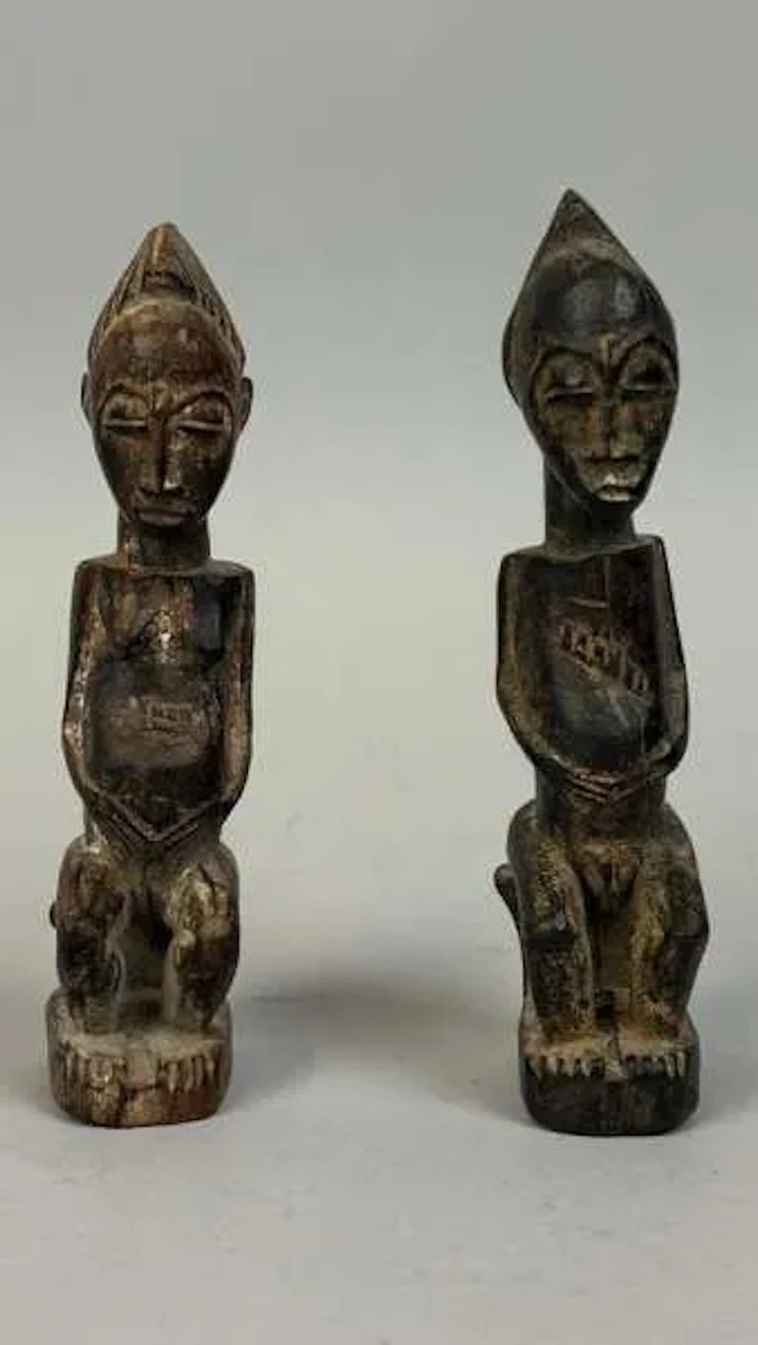 A pair of protective amulets carved from wood with a dark pa - Lot 218