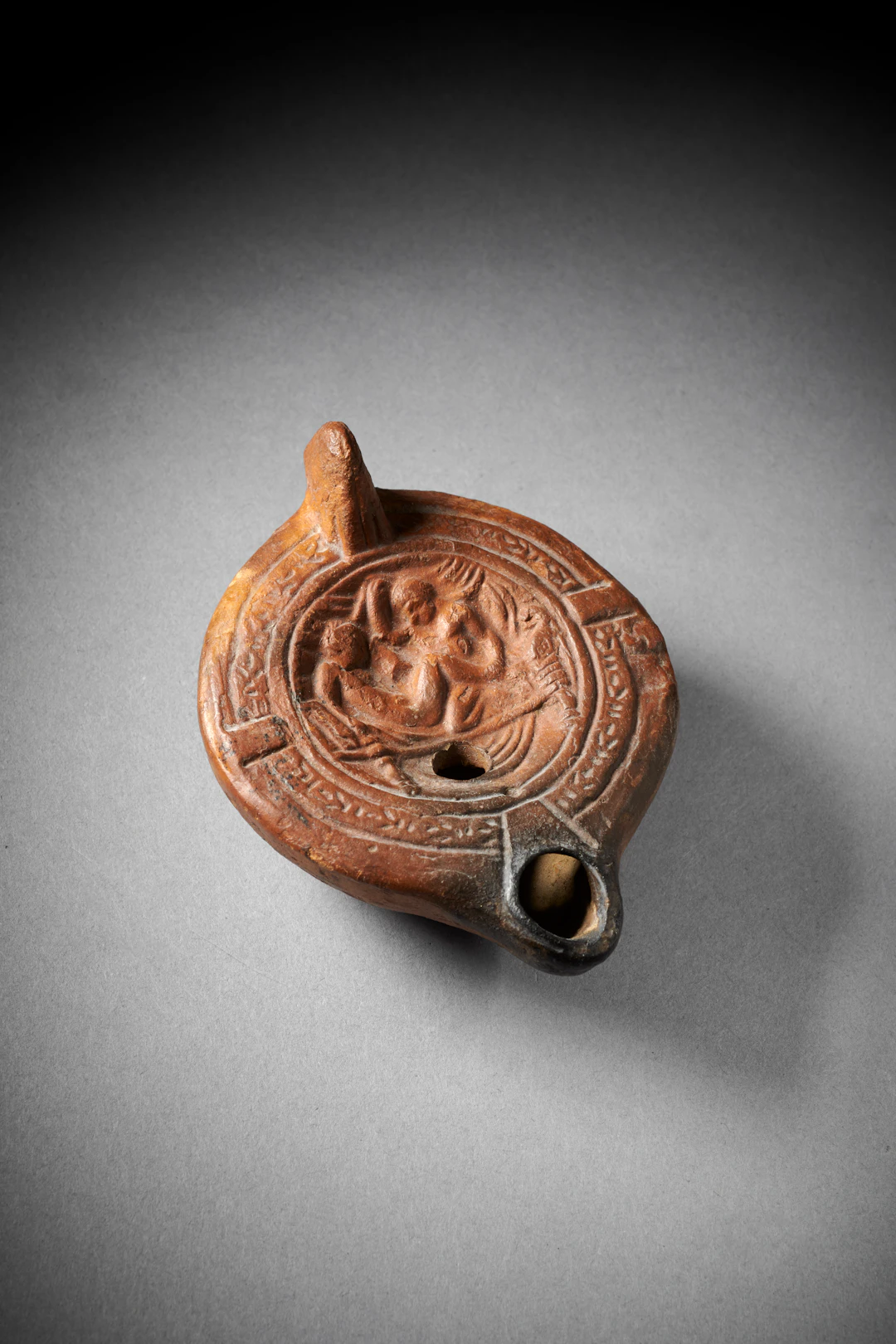 A Roman pottery oil lamp with erotic scene