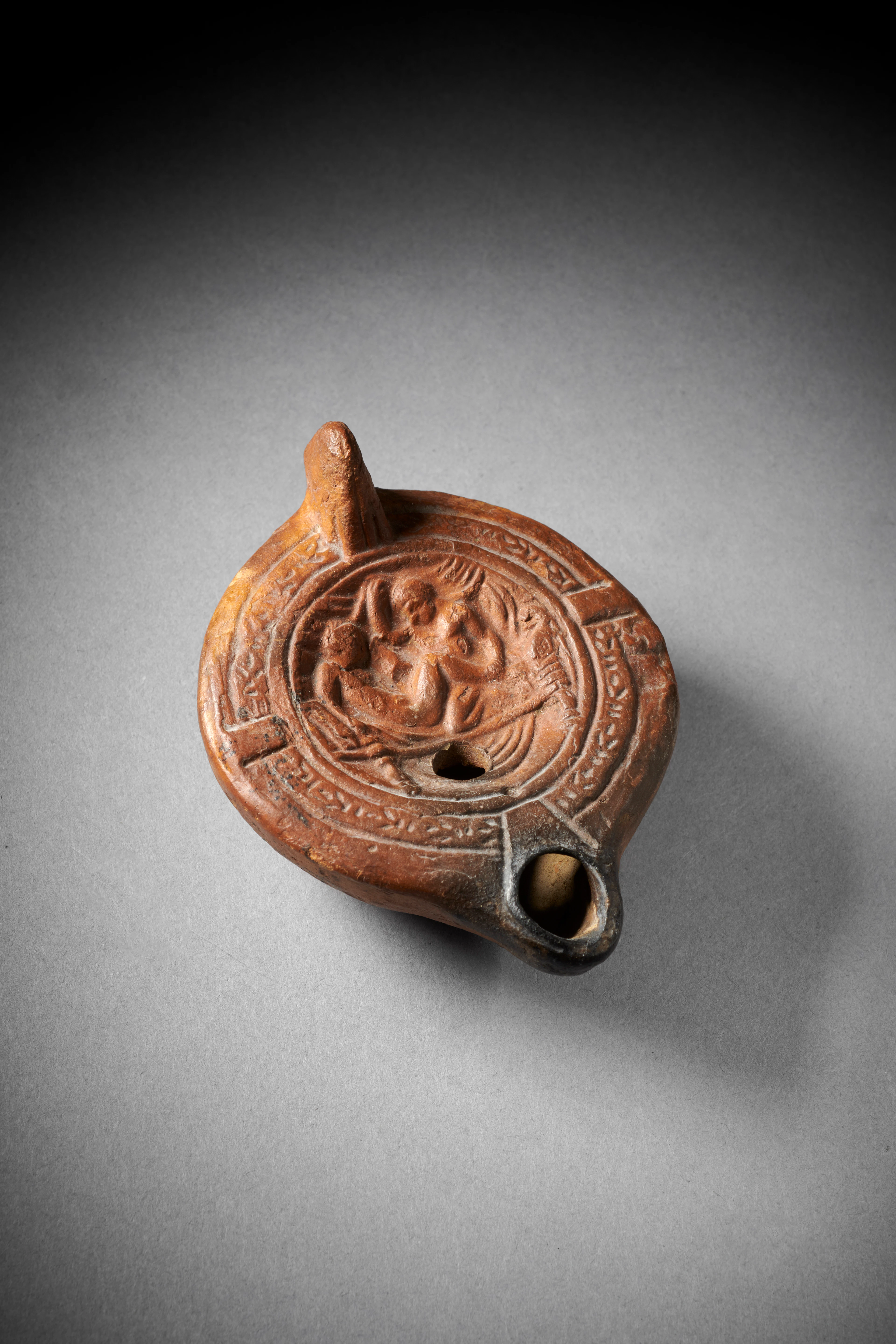A Roman pottery oil lamp with erotic scene