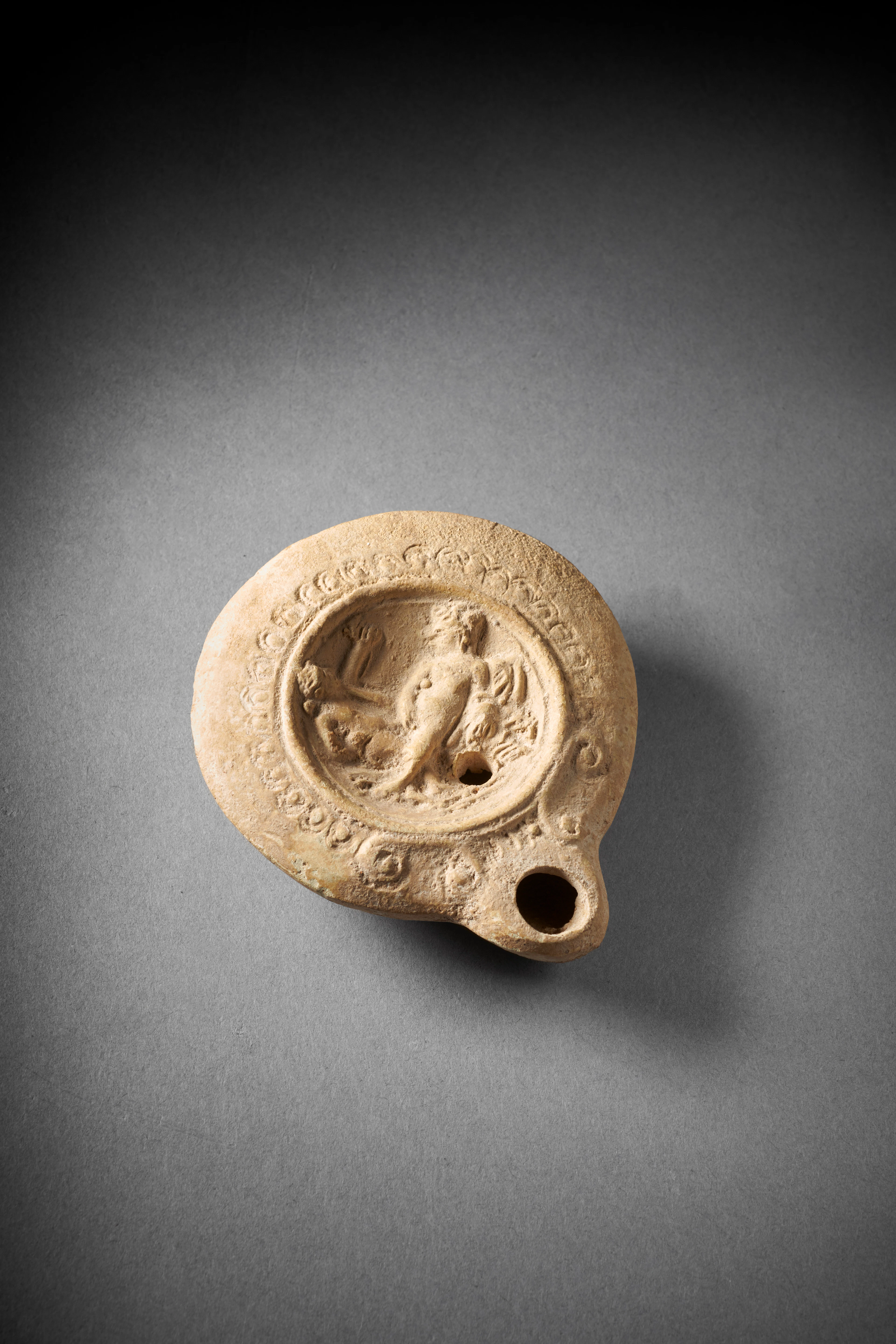 A Roman pottery oil lamp with erotic scene
