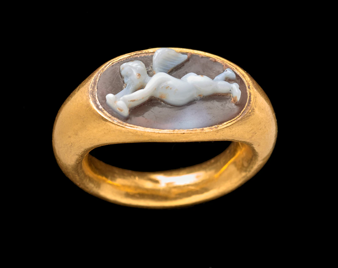 A Roman gold and agate cameo ring with Eros playing an aulos
