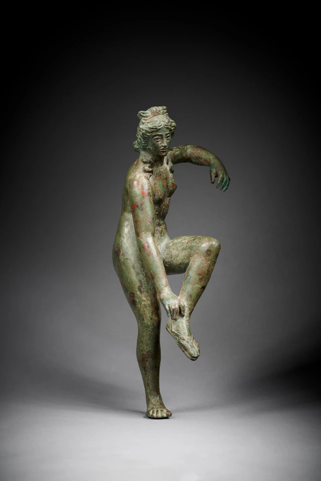 A Roman bronze statuette of Venus loosening her sandal