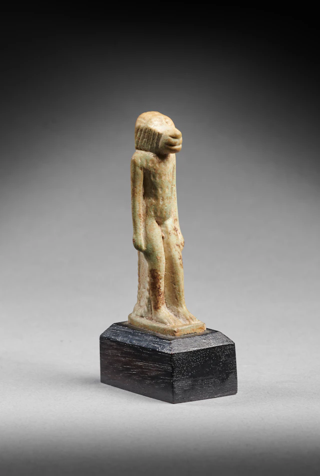 An Egyptian faience amulet of a standing monkey