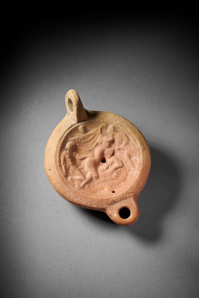 A Roman pottery oil lamp with erotic scene