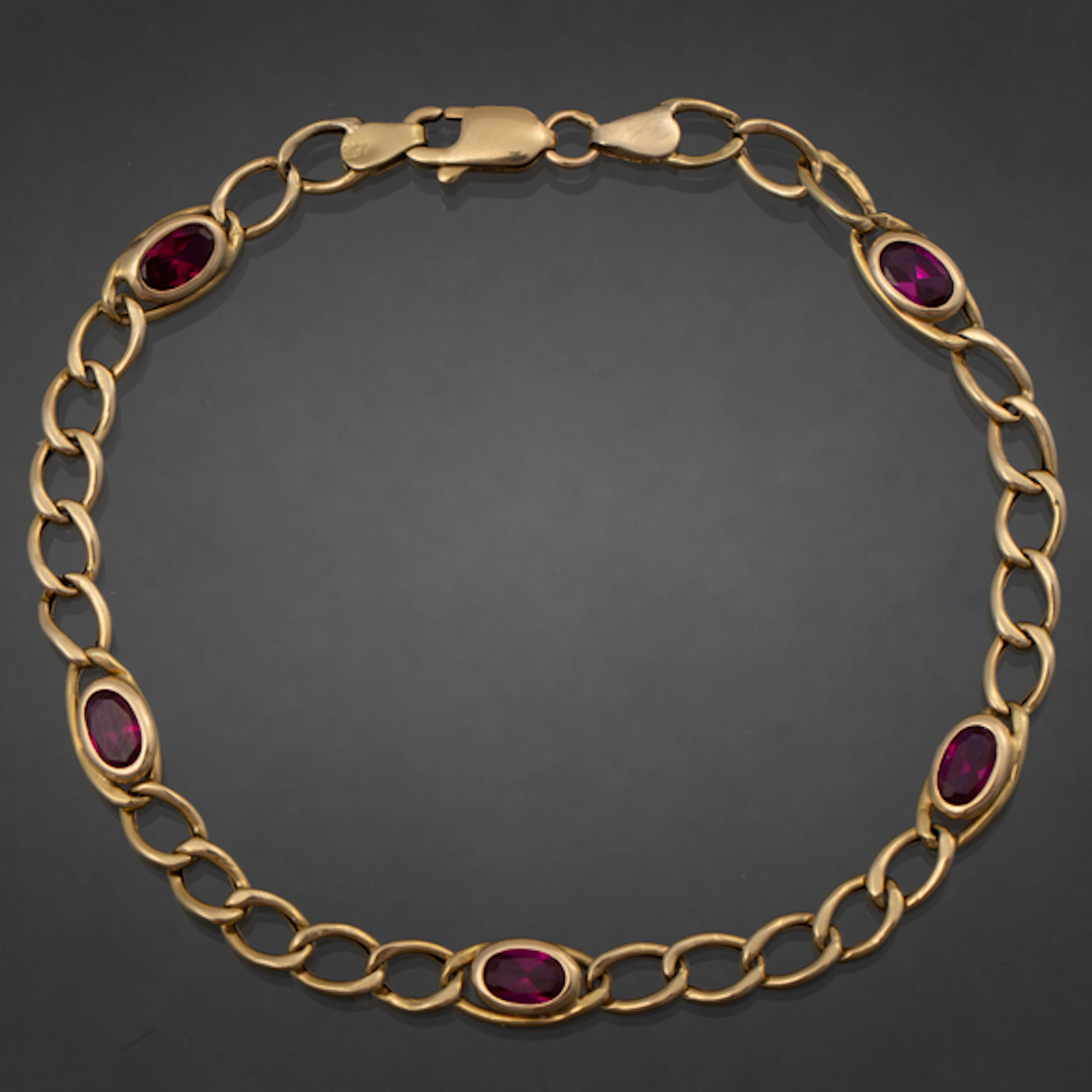 Pulsera en oro amarillo de 18 kt con piedras sintéticas de color rojo.