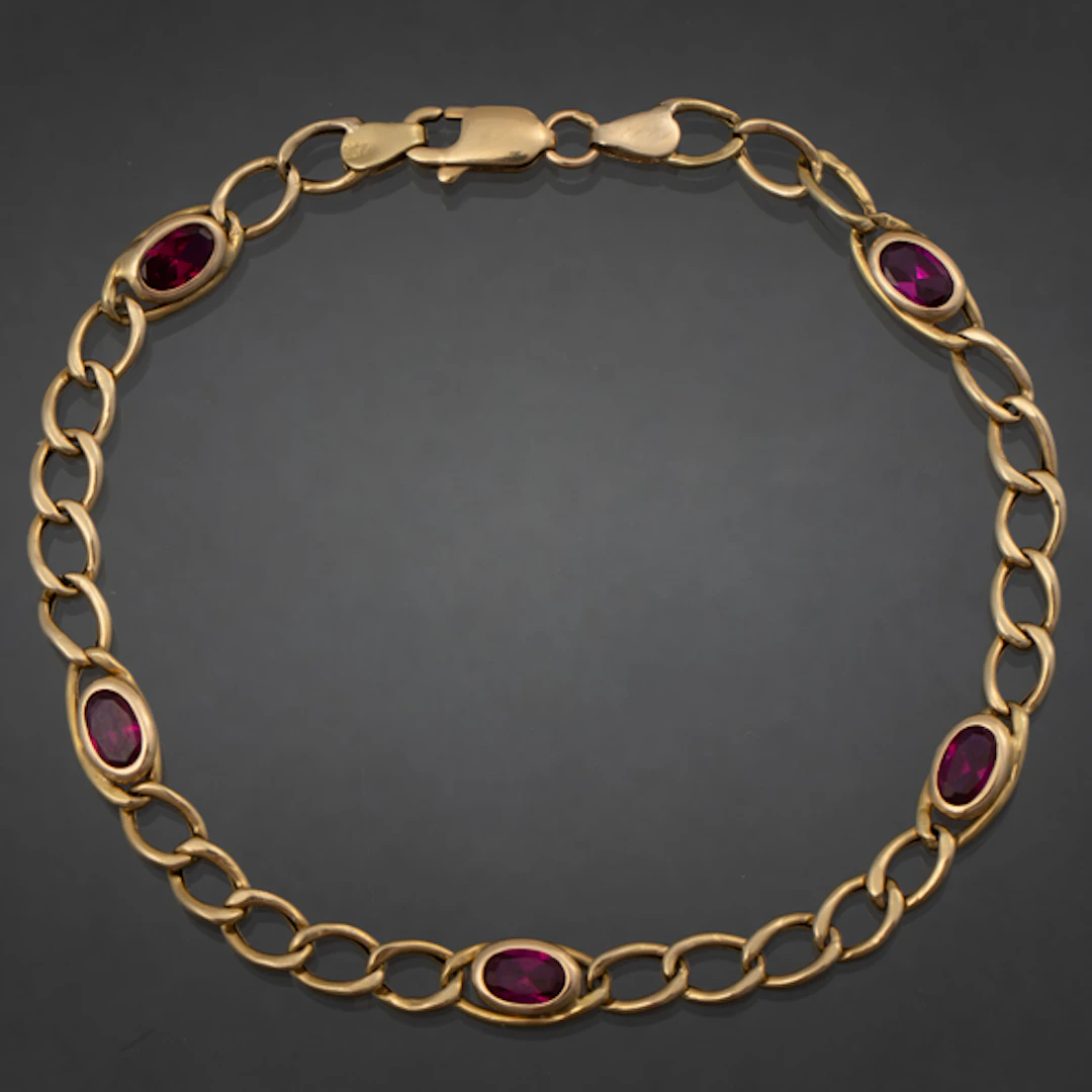 Pulsera en oro amarillo de 18 kt con piedras sintéticas de color rojo.