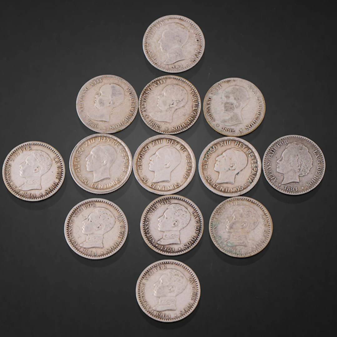 Conjunto de trece monedas de cincuenta céntimos de Alfonso XII y Alfonso