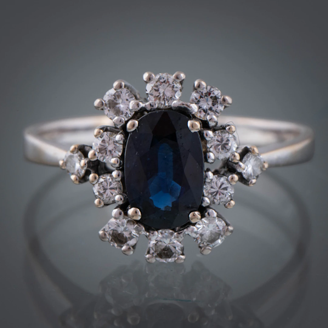 Anillo en oro blanco de 18kt con zafiro central sintético orlado de brillantes.