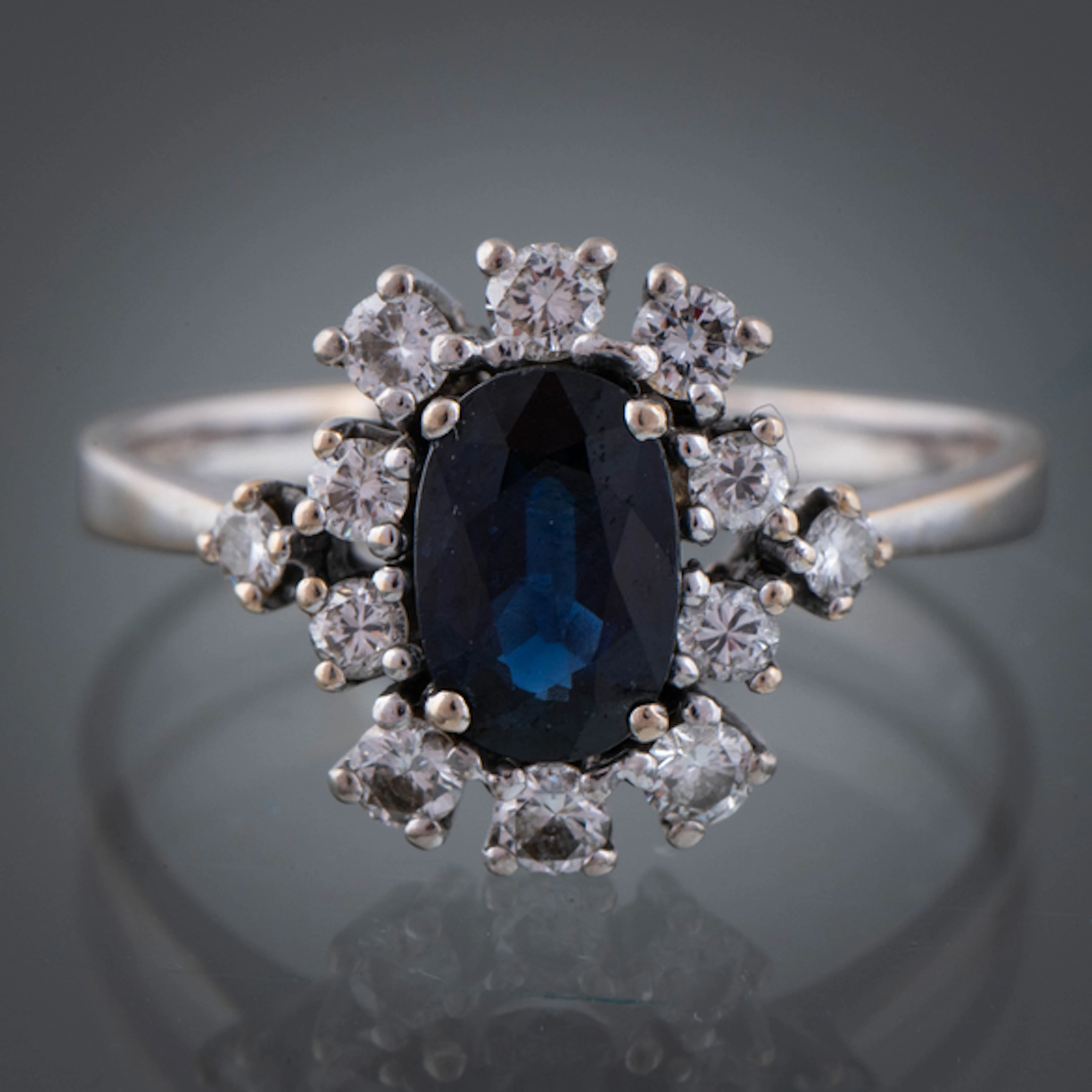 Anillo en oro blanco de 18kt con zafiro central sintético orlado de brillantes.