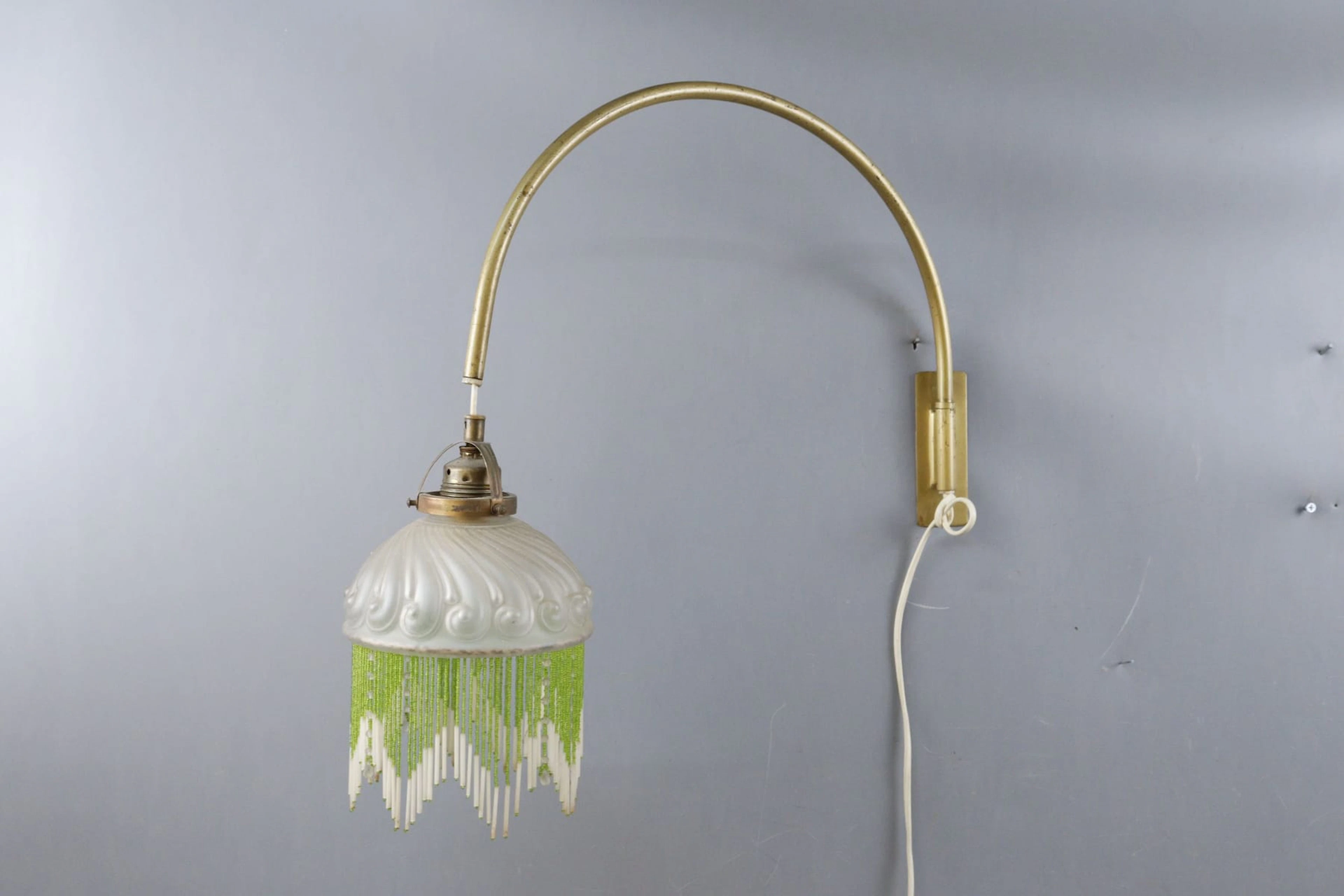 Vägglampa, mässingsarm med glaskupa med fransar