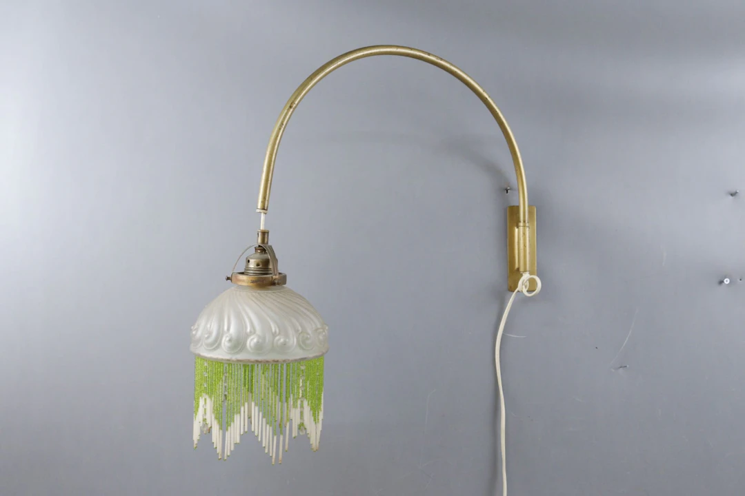 Vägglampa, mässingsarm med glaskupa med fransar