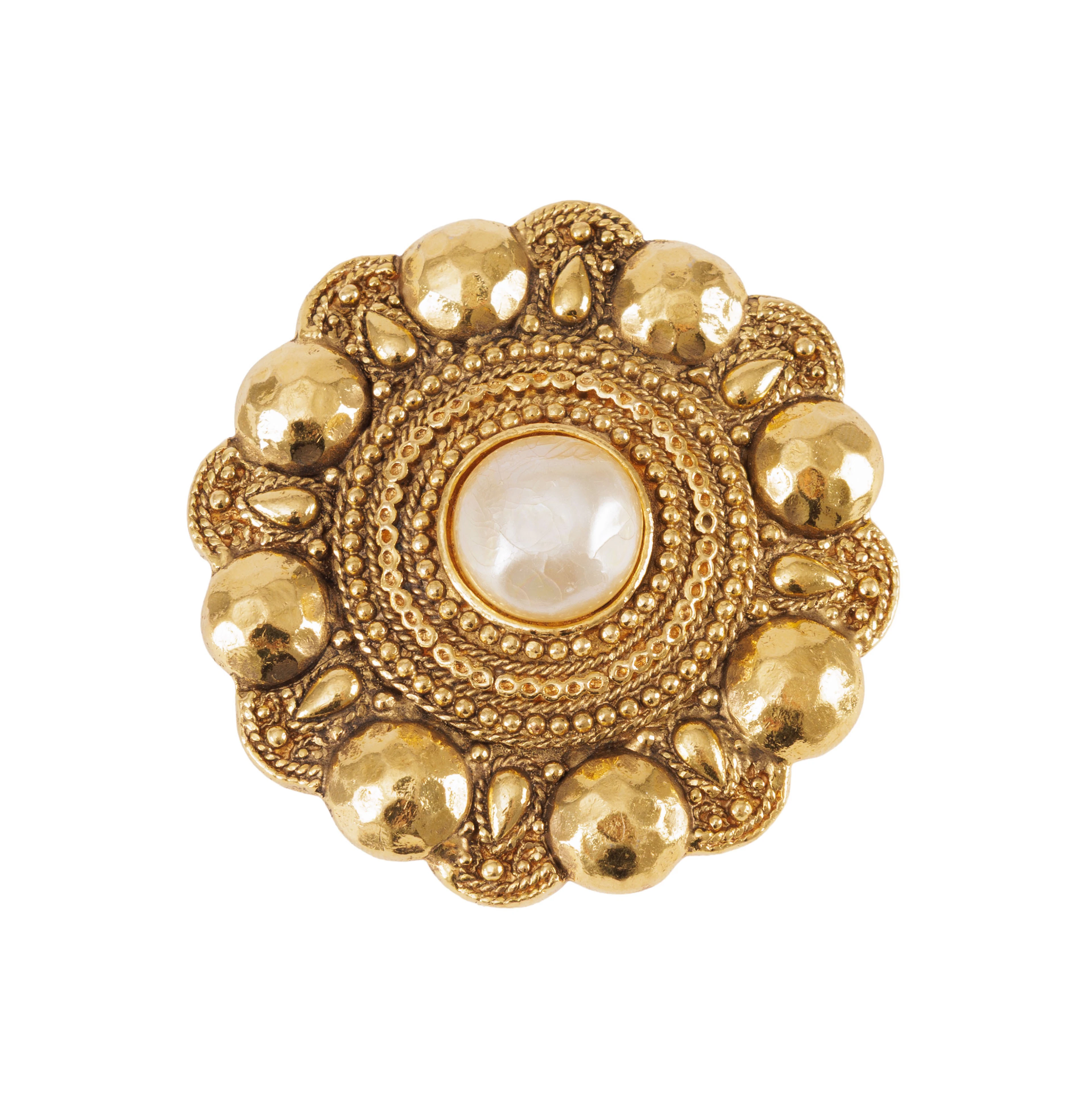 Chanel, broche ronde en métal doré centrée d'une simili perle en cabochon