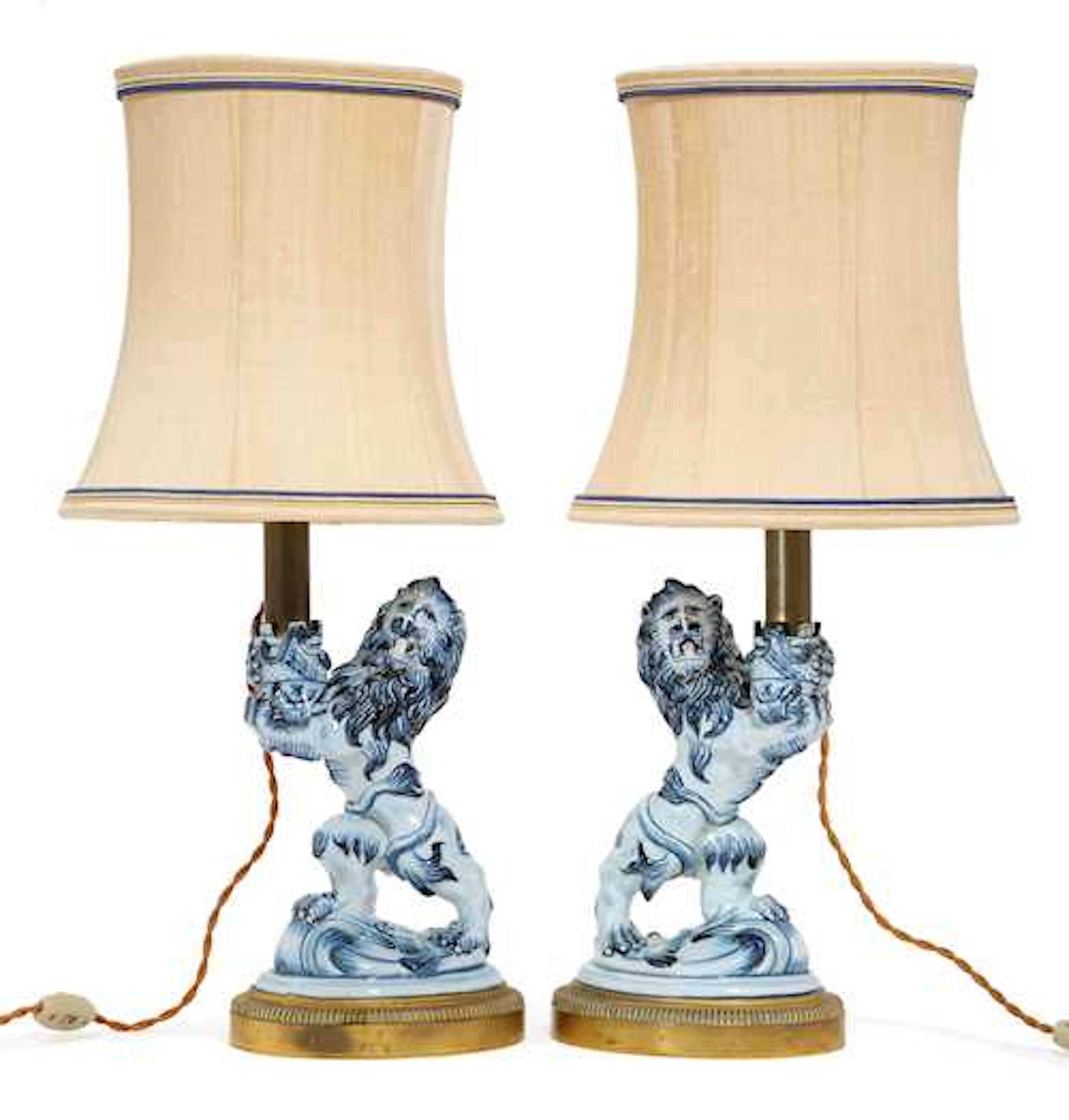 A PAIR OF FAIENCE LIONS MOUNTED AS LAMPS